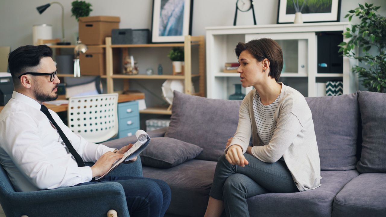why-choose-me A therapist consults with a client during a counseling session on a sofa in an office setting.
